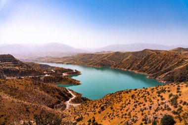 Dağlarla çevrili güzel bir göl ve kuru, kahverengi bir yamaç. Göl mavi ve gökyüzü berrak.