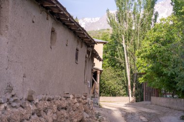 Önünde ağaç olan taştan bir bina. Bina eski ve kırsal bir görünüme sahip. Ağaç uzundur ve yeşil yaprakları vardır. Sahne huzurlu ve huzurlu bir hava veriyor.