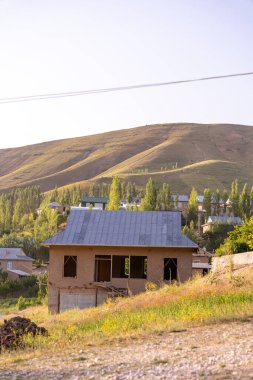 Kırsal bir bölgedeki bir yamaçta küçük bir ev bulunur. Ev eski ve bir sürü karakteri var. Uzakta bazı ağaçlar ile çevre alan çoğunlukla otlaktır. Gökyüzü açık.