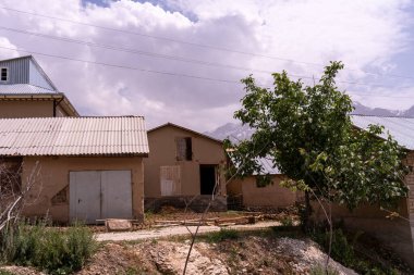 Önünde ağaç olan küçük bir ev. Evin etrafı çitlerle çevrili ve üstünde kablolar var.