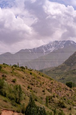 Gökyüzü bulutlu ve dağlar karla kaplı. Dağlar çok yüksek ve gökyüzü çok mavi.