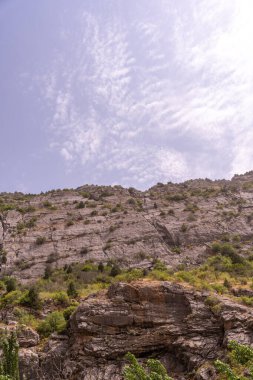 Arkasında bulutlu bir gökyüzü olan bir dağ. Gökyüzü mavi ve bulutlar beyaz