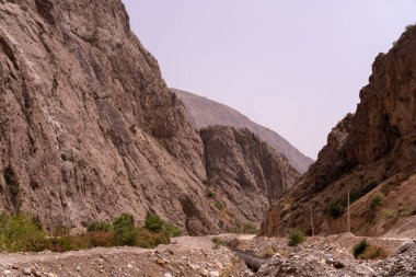 İçinden toprak yol geçen kayalık bir dağ sırası. Yol dar ve dolambaçlı ve çevresi çorak ve kayalık. Sahne yalnızlık ve yalnızlıktır.