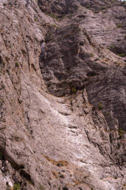 İçinde küçük bir yarık olan kayalık bir dağ. Yarık kayalarla çevrili ve üzerinde birkaç ağaç yetişiyor. Sahne kayalık arazisiyle engebeli ve vahşi.