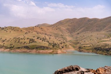 Önünde göl olan güzel bir dağ sırası. Göl sakin ve mavidir ve dağlar ağaçlarla kaplıdır. Sahne huzurlu ve sakin, dağlarla birlikte.