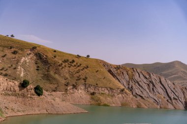 Önünde bir su kütlesi olan bir dağ sırası. Su koyu mavi bir renktir.