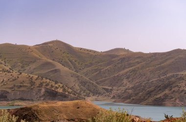 Dağlar ağaçlarla örtülmüş, gökyüzü de berrak. Dağlar çok yüksek ve ağaçlar yeşil.