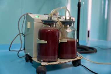 Üzerinde iki şişe bulunan tıbbi bir cihaz. Şişeler kırmızı bir sıvıyla dolu.