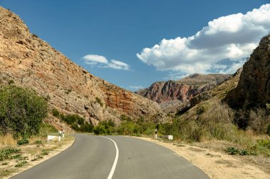 Arka planda dağ olan bir yol. Yol boş ve gökyüzü temiz.