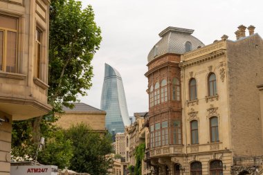 Arka planda yüksek bir bina ve ATM yazan bir tabela olan bir sokak sahnesi. Binalar eski ve cadde ağaçlarla kaplı.