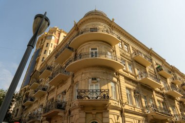 Balkonları ve sokak lambaları olan yüksek bir bina. Binanın bir sürü penceresi ve balkonu var.