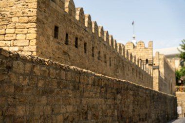 Üzerinde bayrak olan taş bir duvar. Duvar yüksek ve birçok penceresi var.