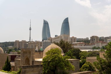 Arka planda uzun bir kule ve tepesinde kubbe olan büyük bir bina olan bir şehir manzarası.