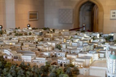 Arkasında büyük bir bina olan bir şehrin modeli. Şehir beyaz plastikten yapılmıştır ve çok fazla detaya sahiptir.
