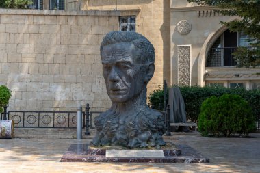 Bir adamın kafasının heykeli bir binanın önünde sergileniyor. Heykel bronzdan yapılmıştır ve eşsiz bir tasarıma sahiptir. Heykel tuğla bir duvarla çevrili mermer bir levhaya yerleştiriliyor.