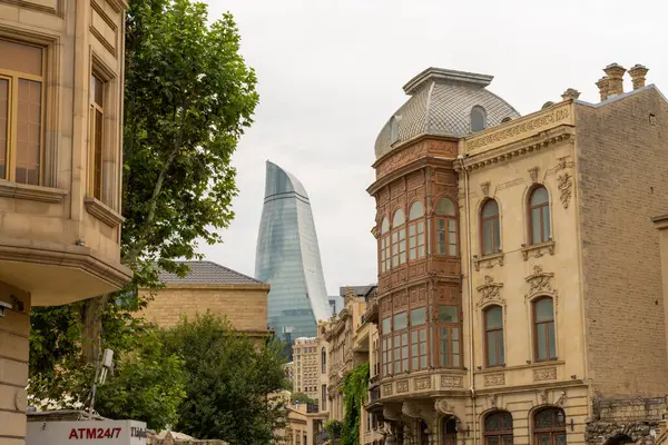 Arka planda yüksek bir bina ve ATM yazan bir tabela olan bir sokak sahnesi. Binalar eski ve cadde ağaçlarla kaplı.