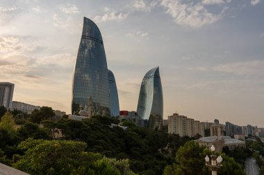 İki bina uzun ve benzersiz bir şekle sahip. Arka planda şehrin ufuk çizgisi görünür.