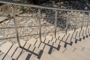 Yerde gölgesi olan metal bir merdiven. Gölge uzun ve ince, merdivenler boyunca uzanıyor. Hareket ve derinlik kavramı, gölge hareket halinde gibi görünüyor.