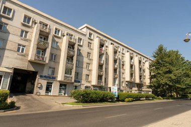 Yan tarafında mavi işareti olan büyük beyaz bir bina. Binanın bir sürü penceresi ve balkonu var.