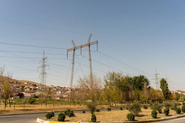 Birkaç ağaç ve birkaç elektrik hattı olan bir kırsal bölge. Gökyüzü açık ve güneş parlıyor.