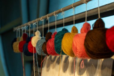 Askıdan sarkan renkli iplikler. Renkler kırmızı, yeşil, sarı ve kahverengi.