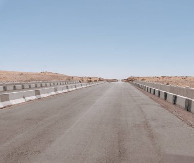 Üzerinde birkaç araba olan bir yol. Yol boş ve hiç insan yok. Gökyüzü açık ve güneş parlıyor.