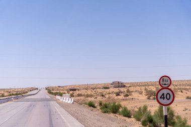 Üzerinde 40 yazan tabelası olan bir yol. Yol boş ve uzakta bir ev var.