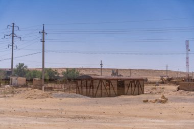 Çölün ortasında küçük bir kulübe var. Gökyüzü açık ve güneş parlıyor.