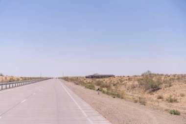 Uzakta bir bina olan bir yol. Yol boş ve gökyüzü temiz.