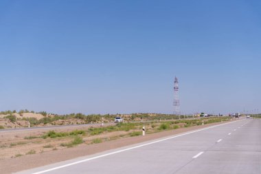 Uzakta yüksek kulesi olan bir yol. Gökyüzü açık ve mavi. Yolda hiç araba yok.