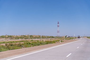 Arka planda uzun bir kule olan bir yol. Yol boş ve trafik yok.