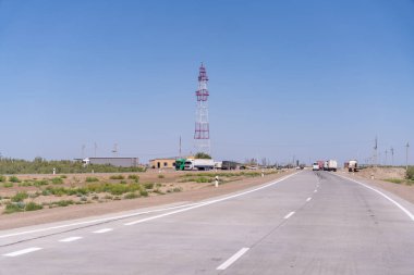 Arka planda uzun bir kule olan bir yol. Yol boş ve üzerinde ne araba ne de kamyon var.