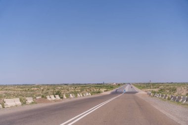 Üzerinde araba olmayan uzun bir yol. Gökyüzü mavi ve berrak. Yol boş ve trafik yok.