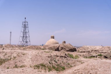 Arkasında kule olan bir çöl manzarası. Gökyüzü açık ve mavi. Kule bir elektrik santrali.