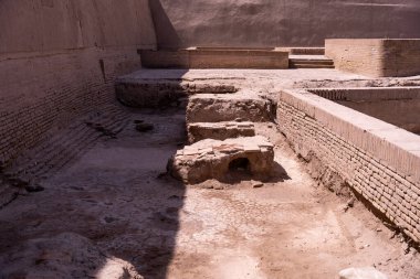 Tuğla duvarı ve taş levhası olan kirli bir avlu.
