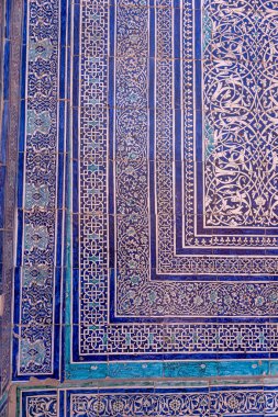 Duvardaki mavi ve beyaz fayans deseni çok karmaşık ve detaylı. Tasarım, geleneksel bir İslami sanat tarzını anımsatıyor.