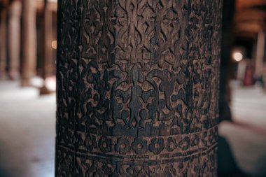 Üzerinde karmaşık oymalar olan tahta bir sütun. Oymalar çok detaylı ve sütun çok eski.