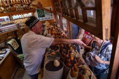 Bir adam bir mağazada baharat satıyor. Bir kadın ondan biraz baharat satın alıyor. Dükkanda başka insanlar da var.