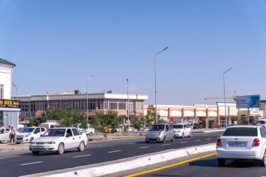 Arabaları ve arka planda binaları olan işlek bir cadde. Sahne hareketli ve aktif