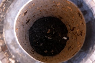 Toprakta içinde siyah bir madde olan bir delik. Çukur kirli ve içinde bir sürü enkaz var.