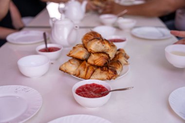 Üzerinde evler olan bir dağ silsilesi. Evler küçük ve çatıları var. Gökyüzü mavi ve güneş parlıyor.