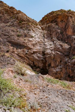 Ortasında küçük bir delik olan kayalık bir dağ. Delik kayalar ve toprakla çevrili. Dağ çorak ve kayalık, görünürde bitki yok. Manzara ıssız ve yalnız.