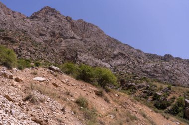 Açık mavi gökyüzü olan bir dağ sırası. Dağ kayalık ve çoraktır. Dağda ne ağaç ne de bitki var.