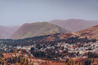 Aşağıdaki vadide küçük bir kasabası olan bir dağ sırası. Gökyüzü açık ve güneş parlıyor.