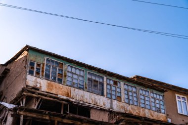 Bir sürü penceresi ve yeşil çatısı olan bir bina. Bina eski ve çok paslı.