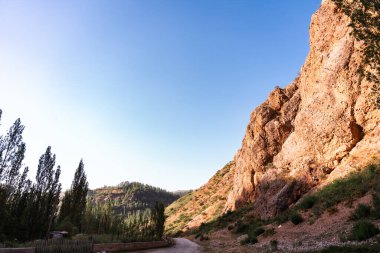 Arka planda açık mavi gökyüzü olan bir dağ sırası. Gökyüzü çok parlak ve güneş parlıyor.