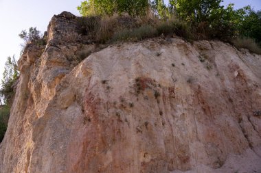 Üzerinde birkaç ağaç büyüyen kayalık bir yamaç. Tepe toprak ve kayalarla kaplı ve ağaçlar seyrek. Sahne, sertlik ve doğal güzelliklerden biridir.