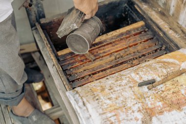 Bir insan ahşap tepsiye bir şey döküyor. Tepsi odunla dolu ve üzerinde bir harita var.
