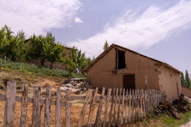 Ahşap çitleri ve toprak bahçesi olan küçük bir ev. Ev eski ve içinde bir sürü çatlak var.
