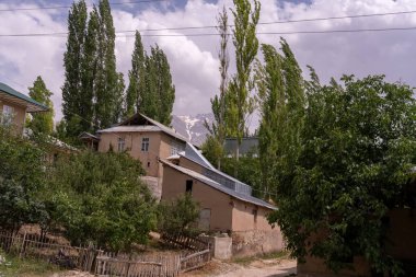 Önünde bir çatı ve ağaç olan bir ev. Evin etrafı ağaçlarla çevrili ve çitleri var.